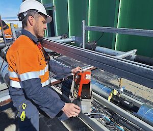 A man in hi-vis checks something with the piping