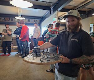 A social gathering with a man showing a wooden board with things on it