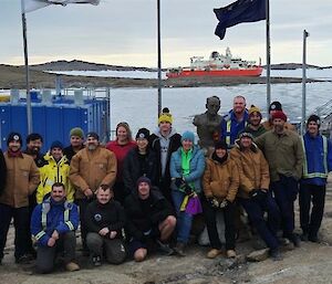 The expeditioners straight off the ship under the flagpoles with the sculpture of Mawson