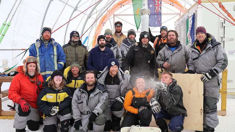 A team of Antarctic expeditioners standing inside a large drilling tent.