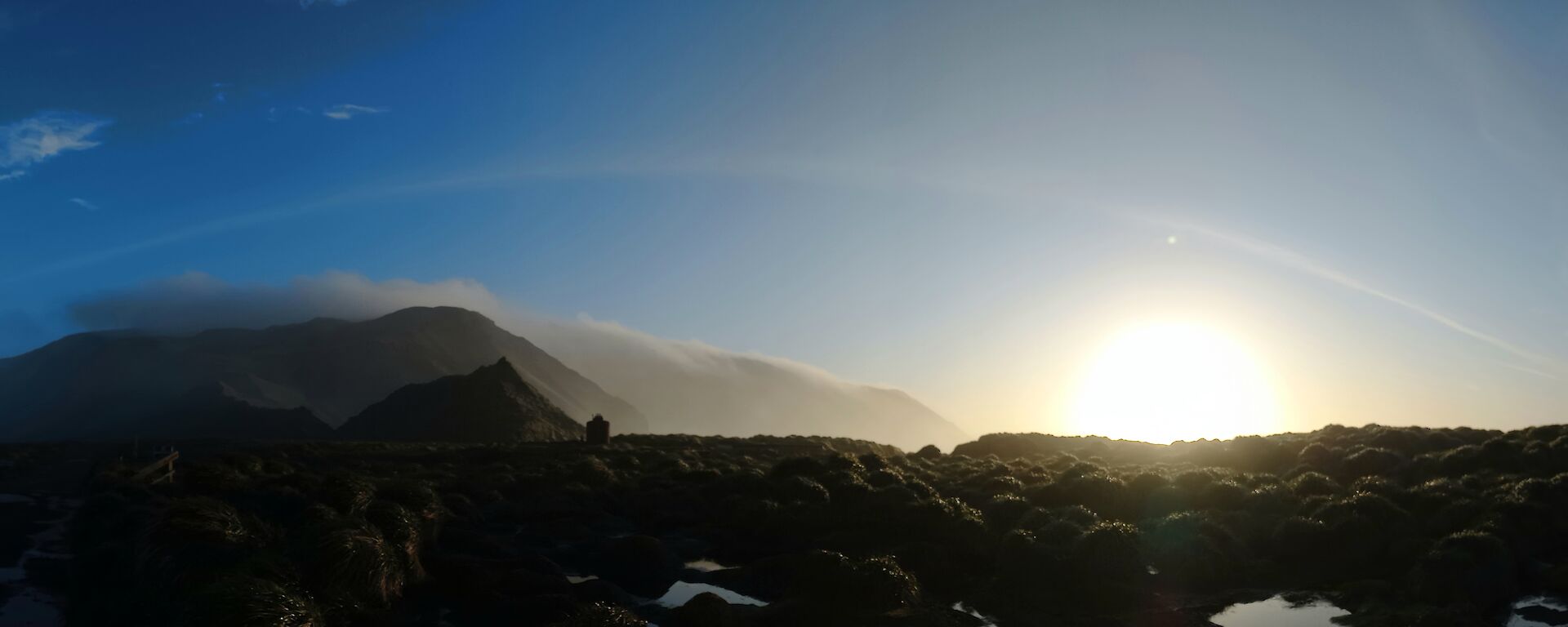 A wispy sweep of cloud over the plateau with bright sun to the right