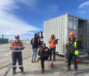 5 expeditioners in front of a shipping container
