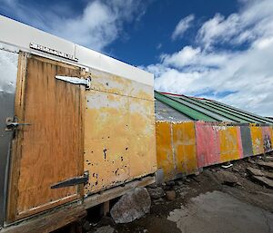 An old building made of different coloured bits of material under a blue sky.