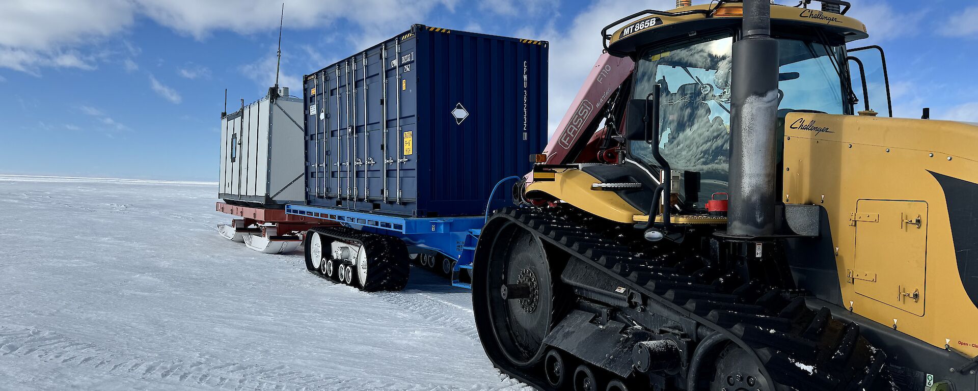 Image of tractor and containers on trailers with snow covered ground.