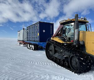 Image of tractor and containers on trailers with snow covered ground.