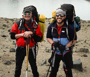 Two mean with hiking packs standing beside a lake