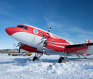 A white and red Basler aircraft parked on snow
