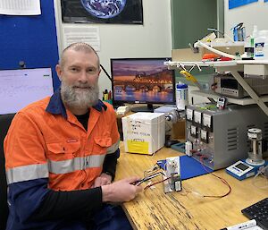 A man in a high-vis work shirt prepares a scientific device for use.