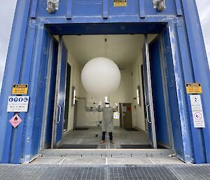 An Antarctic expeditioner holding a large, white balloon.