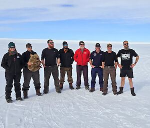 Image of 8 AAD staff in regular clothing with snow covered ground and a blue sky.