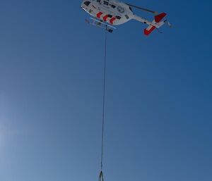 Image of helicopter with object dangling below.