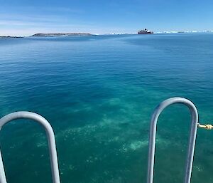 Beautiful still blue bay,with icy cliffs in the far distance