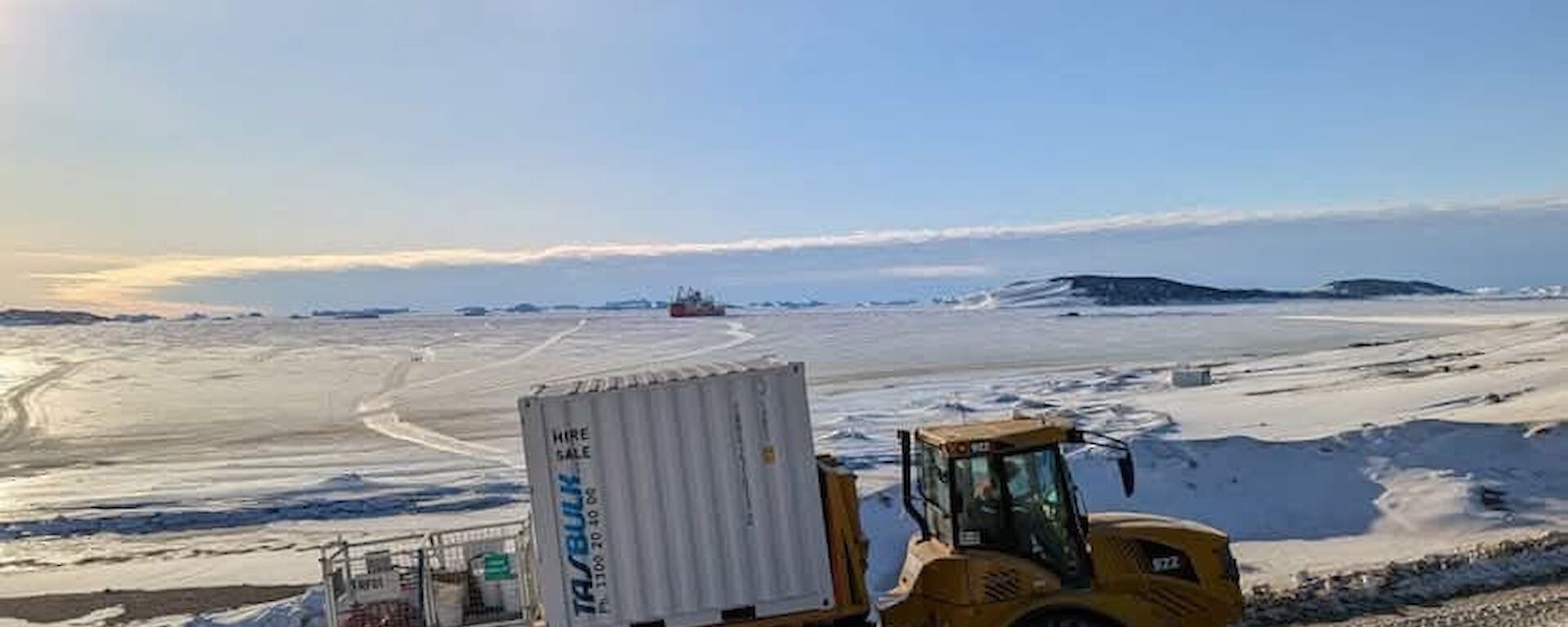 A big white metal box on the back of a flat tray truck with a snowy background