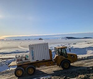 A big white metal box on the back of a flat tray truck with a snowy background