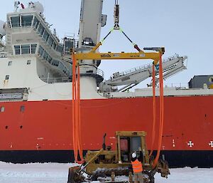 A ship crane about to lift a bulldozer on to the ship