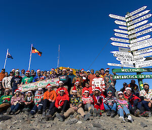 A group photo of people wearing Christmas clothes with the signpost on the right