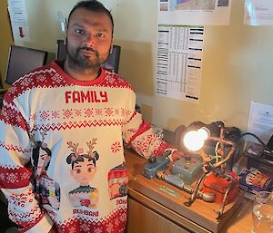 A man wearing the family Christmas jumper, with a piece of electronic equipment