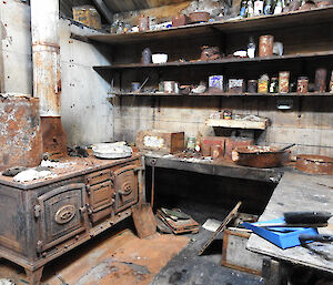 Inside an old hut with ancient stove, shelves and old tins