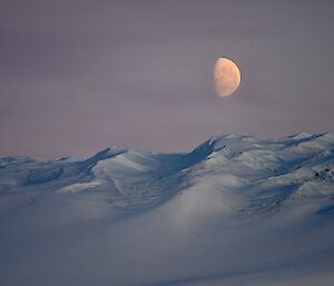 Beautiful photo of a golden moon over icy hills