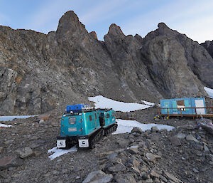 An aqua snow tractor on a snowy rocky hillside