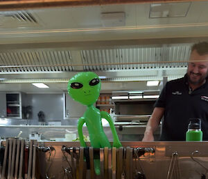 A blow up green alien behind the counter of the ship's kitchen