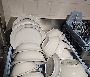 A very crowded draining board, full of bowls and plates