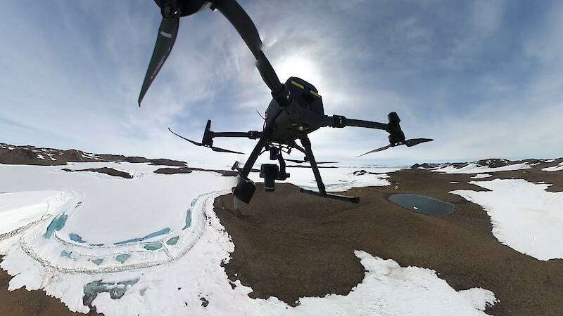 View from beneath a drone taking off over ice and rock