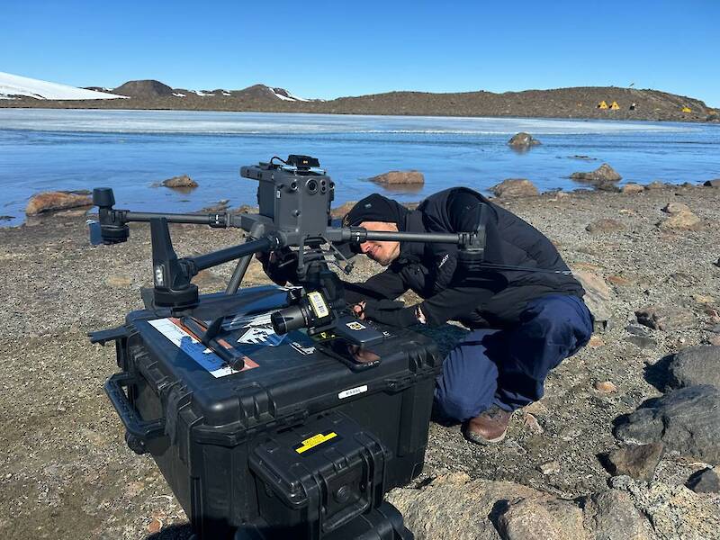 A man working on a drone sitting on a large black box