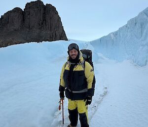 A man in yellow and black outdoor gear on a snowy surface