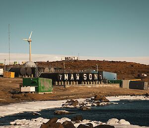 Wide shot of Mawson station buildings with wind turbine in the distance