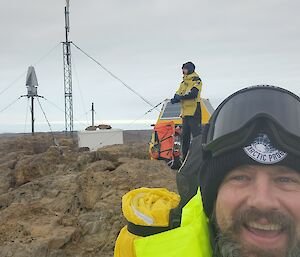 Two Antarctic expeditioners on top of a rocky summit