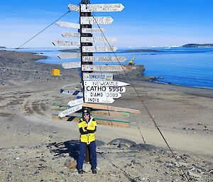 A man standing in front of a signpost overlooking a bay at Davis station