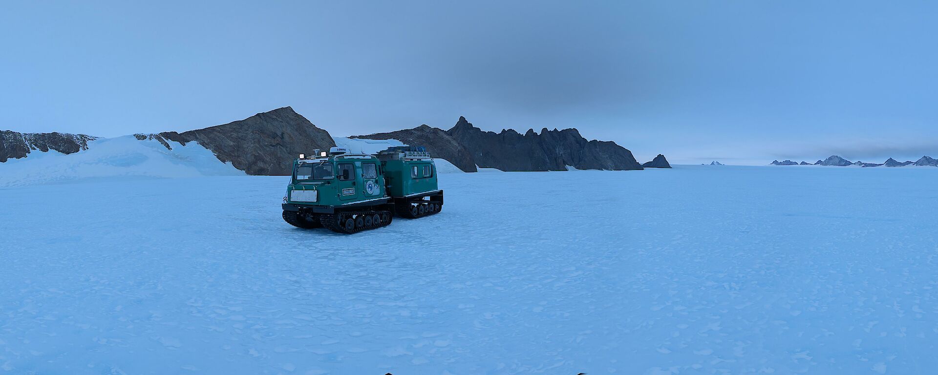 A green tractor against white ice