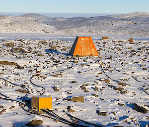 A series of differently shaped boxes linked by black cables, distributed around a large area of snow-covered rocks.