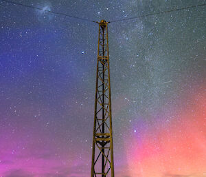 A tower with a pink and green aurora behind