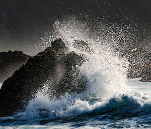 Giant wave crashes against a rocky outcrop