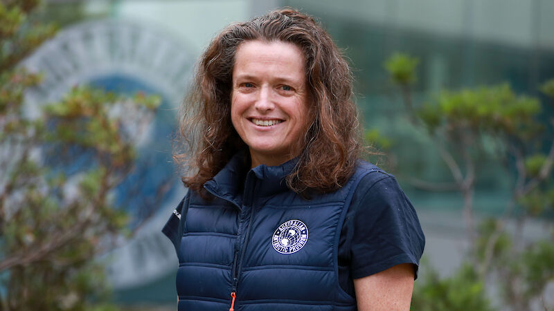 A woman wearing an Australian Antarctic Division puffy jacket standing in a garden