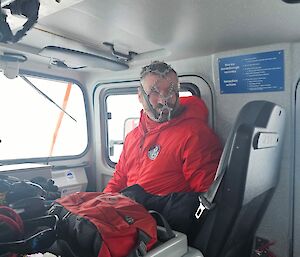 A man in red sitting in a truck with shoe spikes on his face