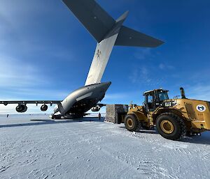 A large aircraft and a heavy tractor on the ice runway
