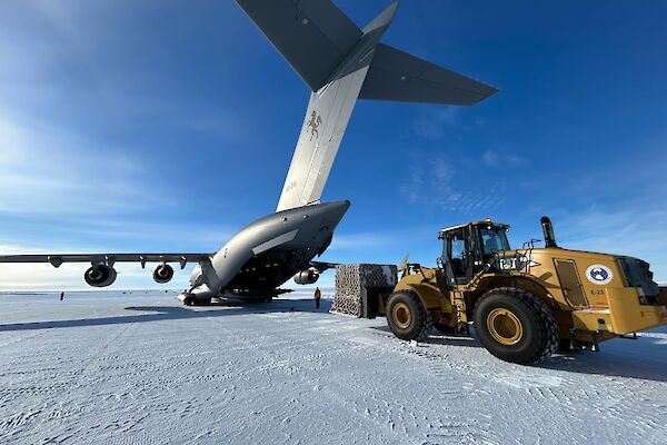 A large aircraft and a heavy tractor on the ice runway