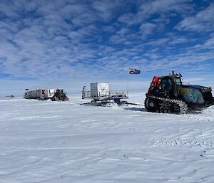 A tractor-train hauling sleds of shipping containers across snow