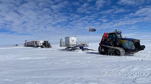 A tractor-train hauling sleds of shipping containers across snow