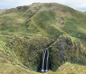 Sawyer Falls central bottom of photo, runs into a circular crater at base of tall grass covered hill which fills the remainder of the photo frame