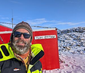 An expeditioner in front of a hut in Antarctica