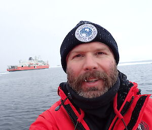 An expeditioner in front of the Nuyina ice breaker
