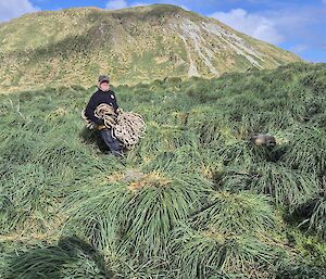 man stands holding bundle of fishing line amongst grass tussocks