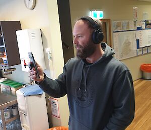 A man with headphones on, on a video call on his phone
