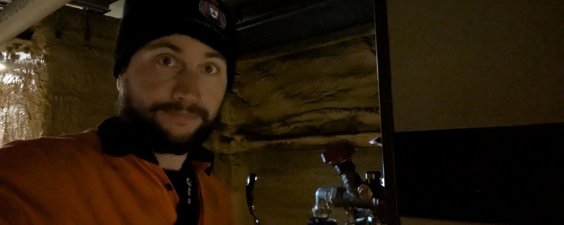 A man in a beanie stands in semi-darkness