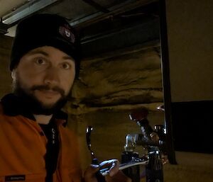 A man in a beanie stands in semi-darkness