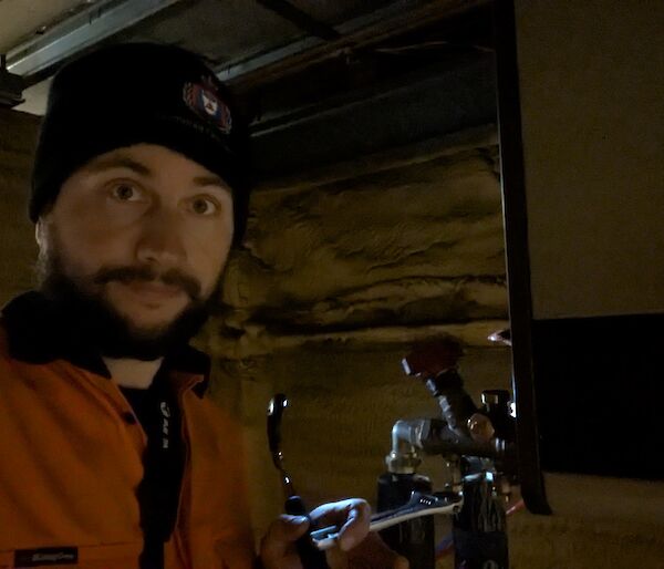 A man in a beanie stands in semi-darkness